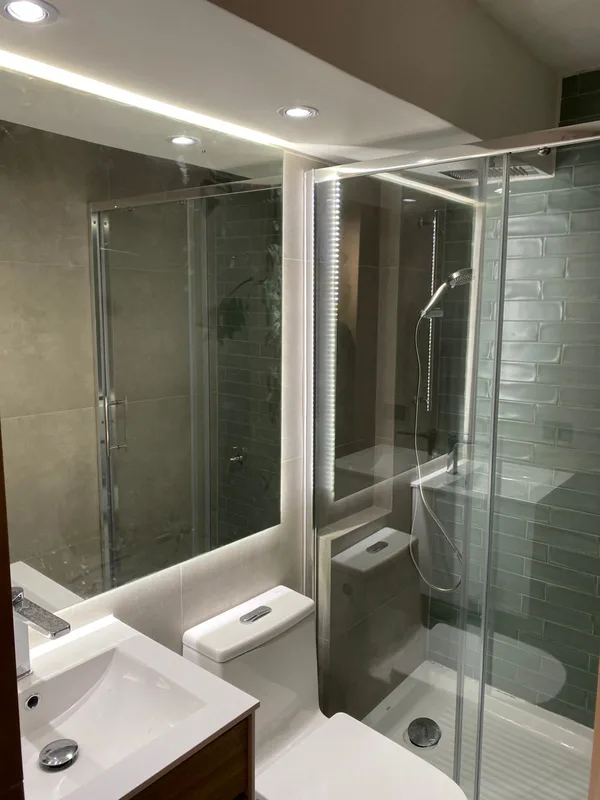 Espejo retroiluminado LED instalado en un baño con ducha de vidrio, Las Condes