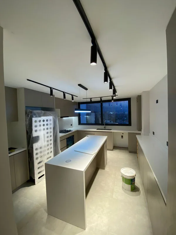 Riel de luces técnicas y lámpara colgante instaladas en una cocina en remodelación, Las Condes