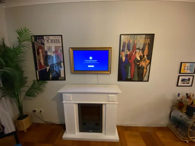 TV tipo marco de arte instalada sobre chimenea en una casa de La Dehesa, Lo Barnechea