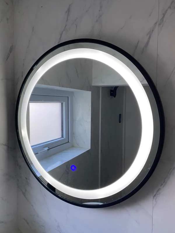 Espejo redondo con luz LED perimetral instalado en un baño de mármol, Vitacura